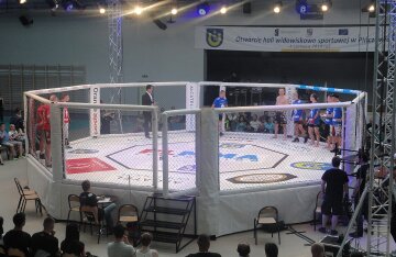An empty MMA octagon cage under arena lights