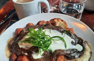 A heaping plate of poutine topped with gravy, cheese curds and green onions