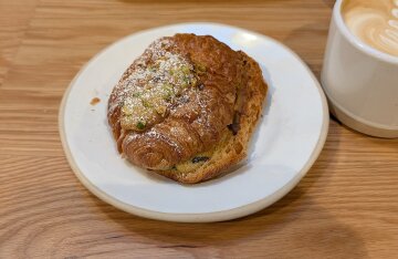 A filled croissant with pistachio and chocolate cream on a bakery counter